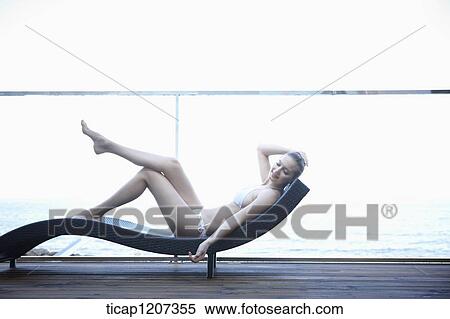 a lady in bikini lying on a beach bed View Large Photo Image Stock Photography - a lady in bikini lying on a beach bed. Fotosearch