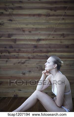 a lady in bikini posing while sitting on wooden floor View Large Photo Image Picture - a lady in bikini posing while sitting on wooden floor. Fotosearch