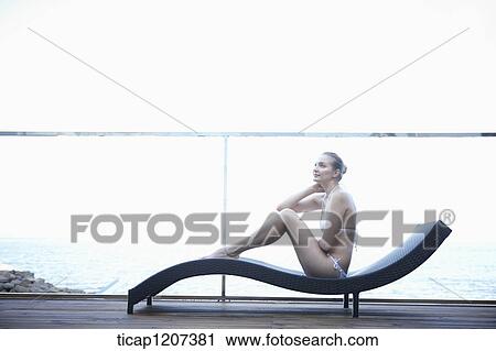 a lady in bikini posing while sitting on a beach bed View Large Photo Image Stock Image - a lady in bikini posing while sitting on a beach bed. Fotosearch