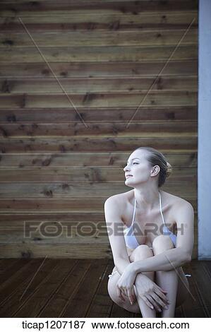 Stock Photo - a lady in bikini posing while sitting on wooden floor. Fotosearch