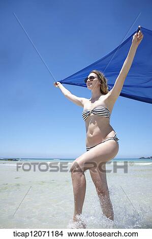 Picture - a lady in bikini running with blue cloth. Fotosearch
