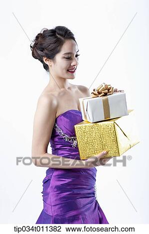 Stock Image - a lady in fancy purple dress holding a pile of gifts. Fotosearch