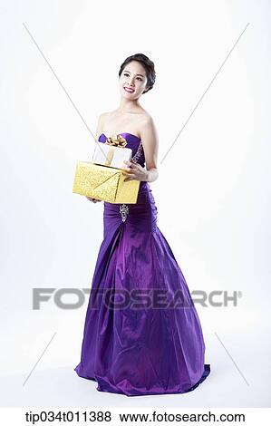 Stock Photo - a lady in fancy purple dress holding a pile of gifts. Fotosearch