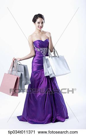 Stock Image - a lady in fancy purple dress posing with shopping bags. Fotosearch