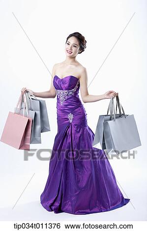 Stock Photograph - a lady in fancy purple dress posing with shopping bags. Fotosearch