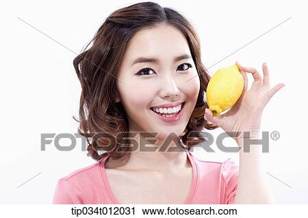 Stock Image - a lady in pink shirt posing with a lemon. Fotosearch