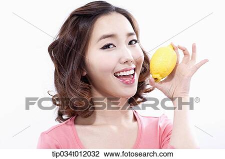 Stock Image - a lady in pink shirt posing with a lemon. Fotosearch
