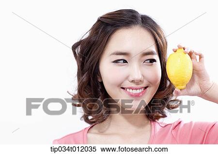 Stock Photography - a lady in pink shirt posing with a lemon. Fotosearch