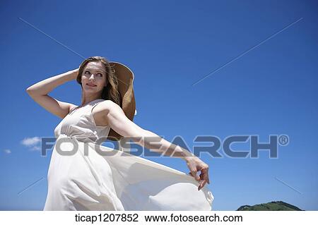 Stock Image - a lady in white dress feeling the breeze. Fotosearch