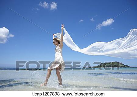 Stock Photo - a lady running on the beach with white cloth. Fotosearch