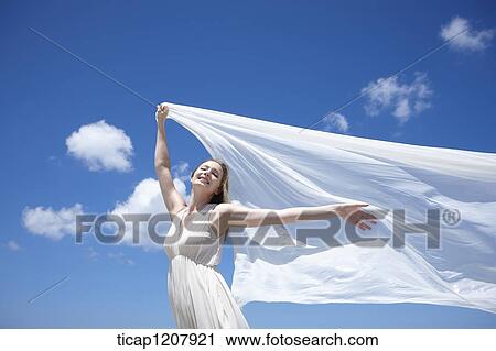 Stock Image - a lady running with white cloth under bright sky. Fotosearch