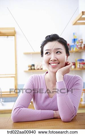 Stock Image - a lady smiling while sitting at table. Fotosearch