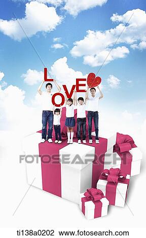 Stock Image - a loving family standing on a present. Fotosearch