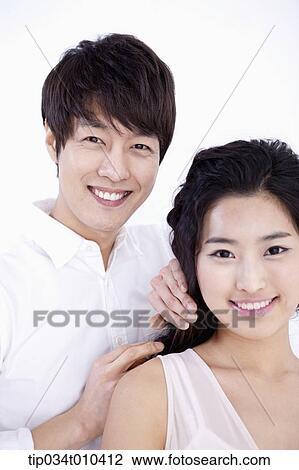 Stock Image - a male hairdresser taking care of woman's hair . Fotosearch