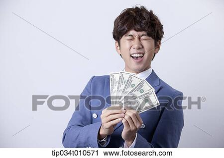 Stock Image - a man looking happy while holding dollars . Fotosearch