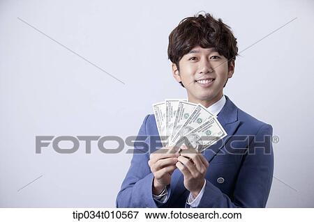 Stock Photo - a man looking happy while holding dollars . Fotosearch