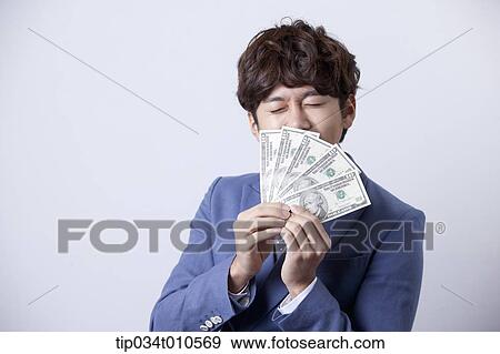 Stock Photo - a man looking happy while holding dollars . Fotosearch