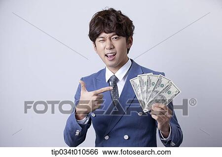 Stock Photograph - a man looking happy while holding dollars . Fotosearch