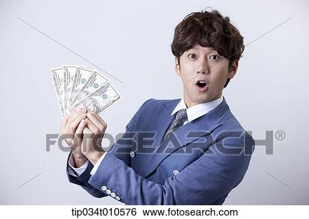 Stock Photograph - a man looking happy while holding dollars . Fotosearch