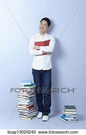 Stock Image - a man next to a pile of books. Fotosearch
