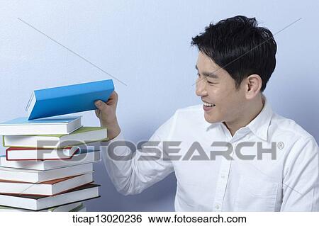 Stock Photograph - a man next to a pile of books. Fotosearch