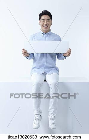 Stock Image - a man sitting with a blank paper. Fotosearch