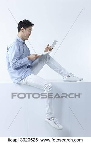 Stock Photography - a man sitting with a laptop. Fotosearch