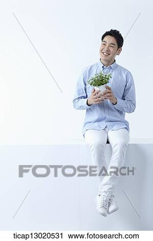 Stock Image - a man sitting with a plant. Fotosearch