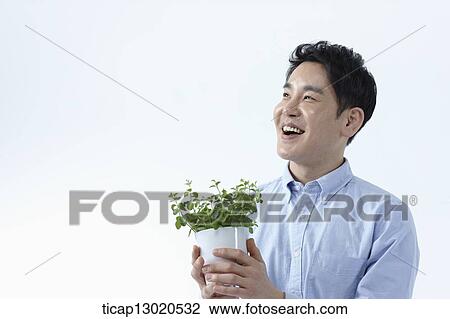Stock Image - a man sitting with a plant. Fotosearch