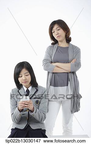 Stock Photo - a mother and a daughter with school uniform and a phone. Fotosearch
