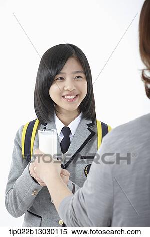 Stock Photography - a mother giving a glass to daughter in a school uniform. Fotosearch