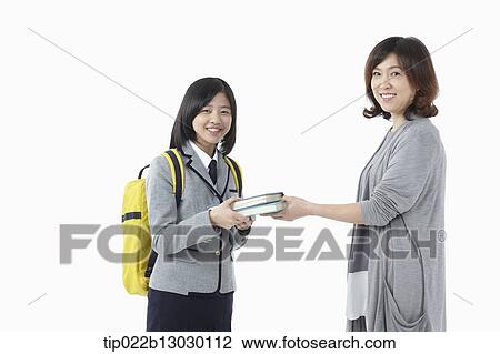 Stock Image - a mother giving school books to daughter in a school uniform. Fotosearch