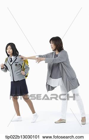 Stock Image - a mother grabbing daughter in a school uniform. Fotosearch