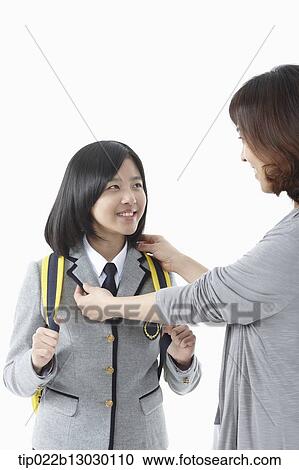 Stock Image - a mother grabbing daughter in a school uniform. Fotosearch