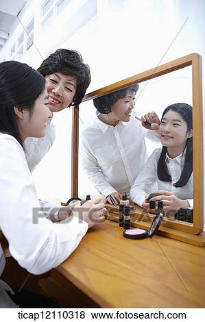 Stock Photo - a mother putting on make up for daughter. Fotosearch