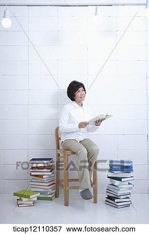 a mother sitting on a chair reading a book View Large Photo Image Stock Photo - a mother sitting on a chair reading a book. Fotosearch