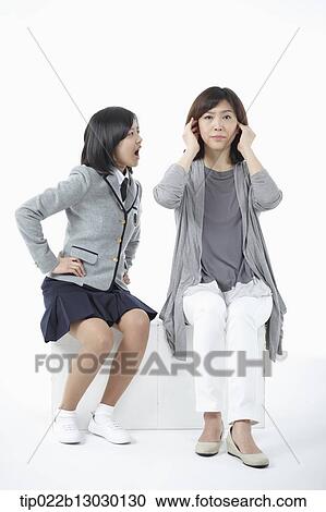Stock Image - a mother sitting with daughter with a school uniform. Fotosearch