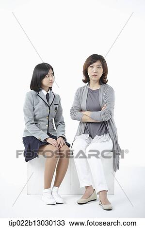 Stock Image - a mother sitting with daughter with a school uniform. Fotosearch