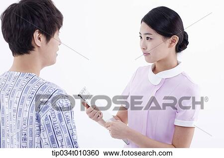 Stock Image - a nurse measuring a patient's body temperature. Fotosearch