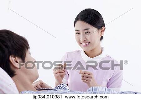 Stock Image - a nurse talking with a patient on a bed. Fotosearch
