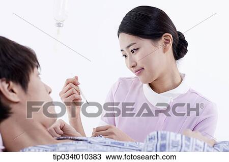 Stock Image - a nurse talking with a patient on a bed. Fotosearch