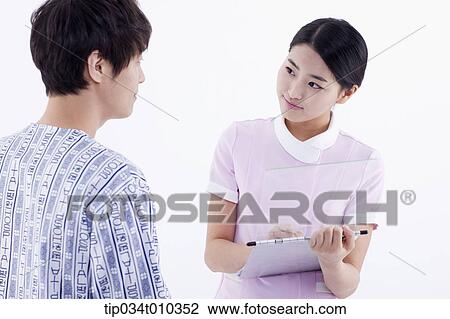 Stock Image - a nurse writing on a report while talking to a patient. Fotosearch