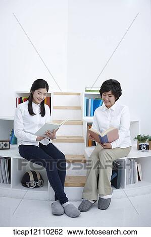 a student and mother sitting on bookshelf reading View Large Photo Image Stock Image - a student and mother sitting on bookshelf reading. Fotosearch