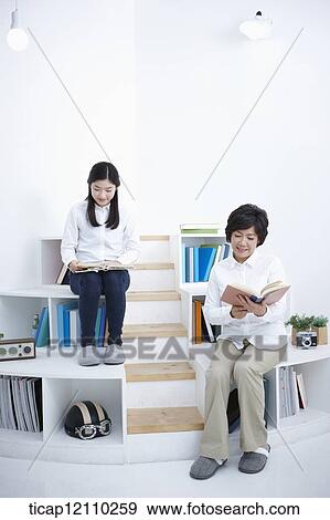 a student and mother sitting on bookshelf reading View Large Photo Image Stock Photo - a student and mother sitting on bookshelf reading. Fotosearch