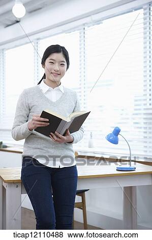 Stock Photo - a student holding a book in classroom. Fotosearch