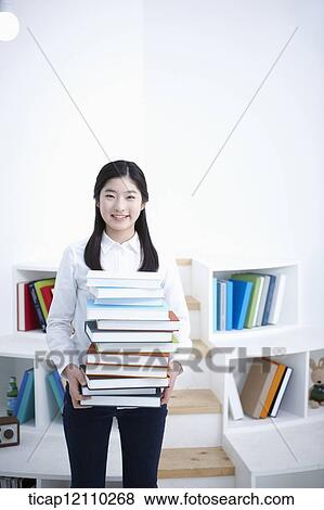 Stock Photo - a student holding a pile of books. Fotosearch