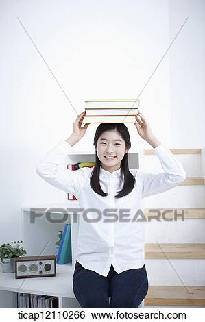 Stock Photograph - a student holding a pile of books. Fotosearch