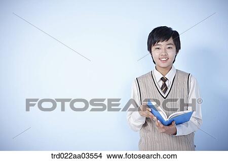 a student in uniform holding a book View Large Photo Image Picture - a student in uniform holding a book. Fotosearch