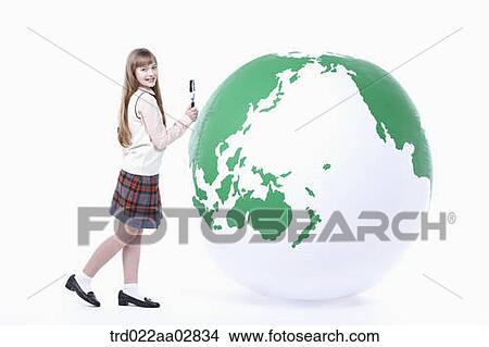 a student in uniform next to a globe with magnifier View Large Photo Image Picture - a student in uniform next to a globe with magnifier. Fotosearch