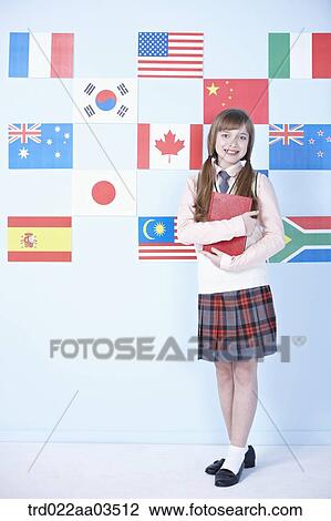 Stock Image - a student in uniform posing in front of international flags with a book. Fotosearch